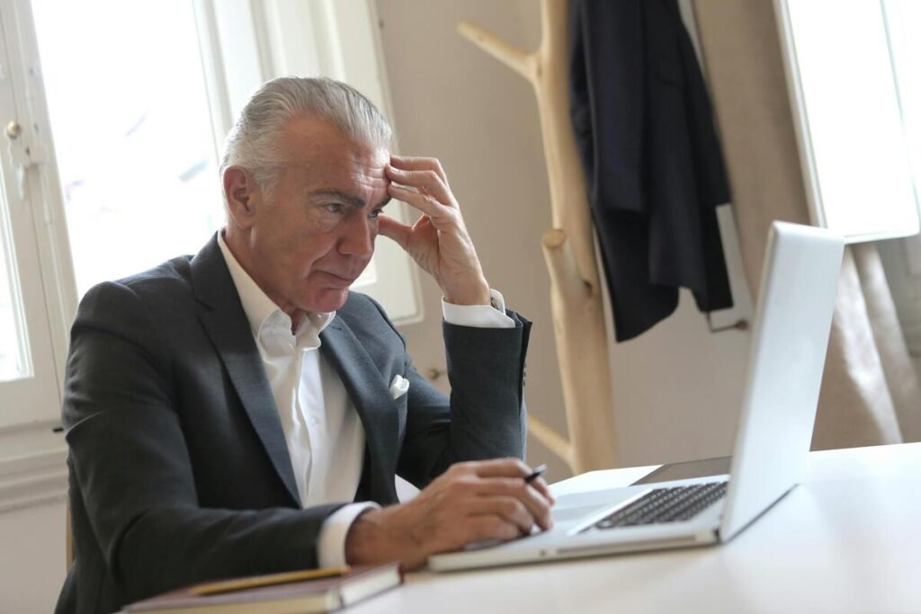 A man in a black suit using a laptop