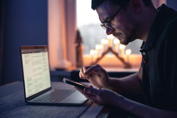 Man browsing on phone and laptop