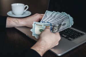 Man holding cash near laptop