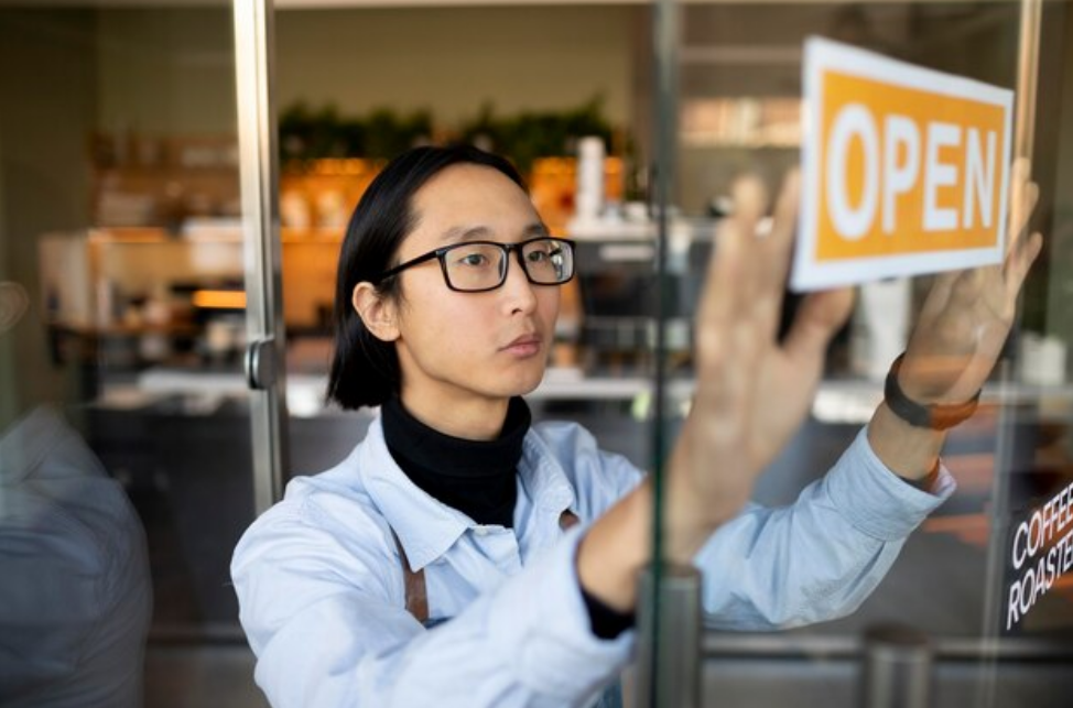 A business store putting up the open sign 4 1