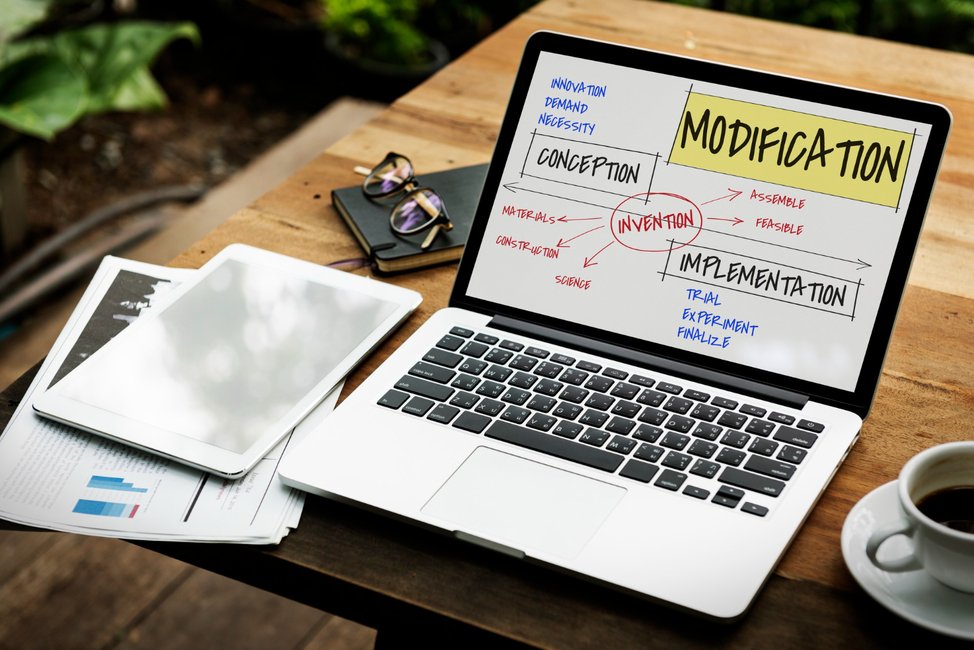 Monthly SEO workflow diagram shown on laptop screen with coffee and documents.