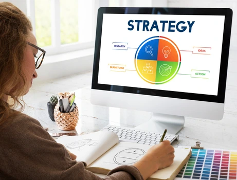 Professional creating SEO strategy plan on desktop with colorful charts and supplies.