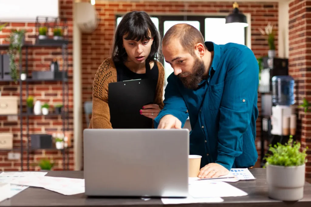 Two people working side-by-side to compare the guest post creation vs niche edit on a desk